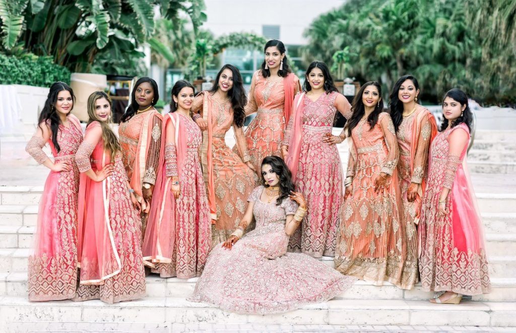 Bride in pink lehenga, glowing.